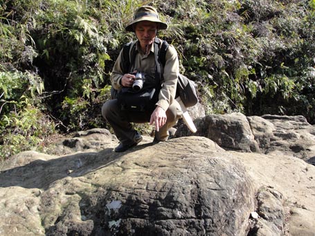 Ông Trần Ngọc Lâm bên một tảng đá ở bãi đá có hình khắc chưa từng được biết đến trong rừng Hoàng Liên Sơn